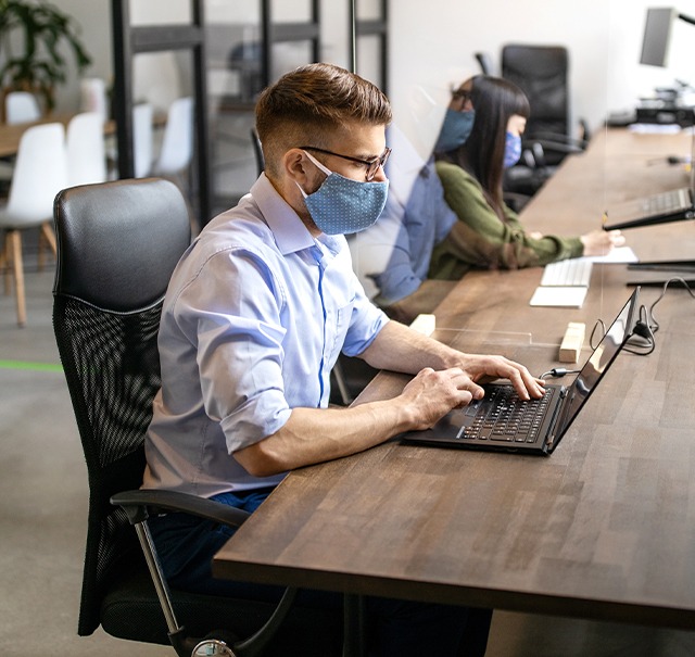 在开放式办公室工作的蒙面人员